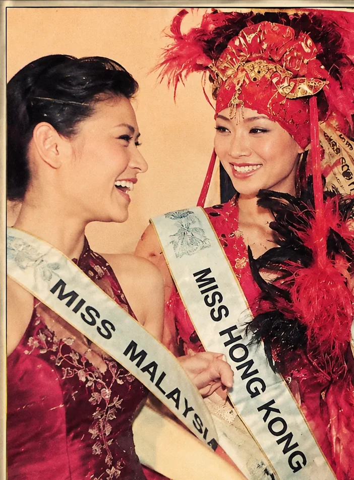 Restored 2005 press photo: Goey, in the Miss Malaysia sash, laughing with Miss Hong Kong