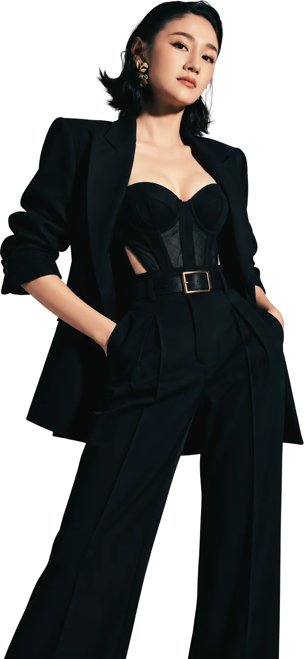 Nico in a black blazer over a corset top and belted wide trousers, hands in her pockets