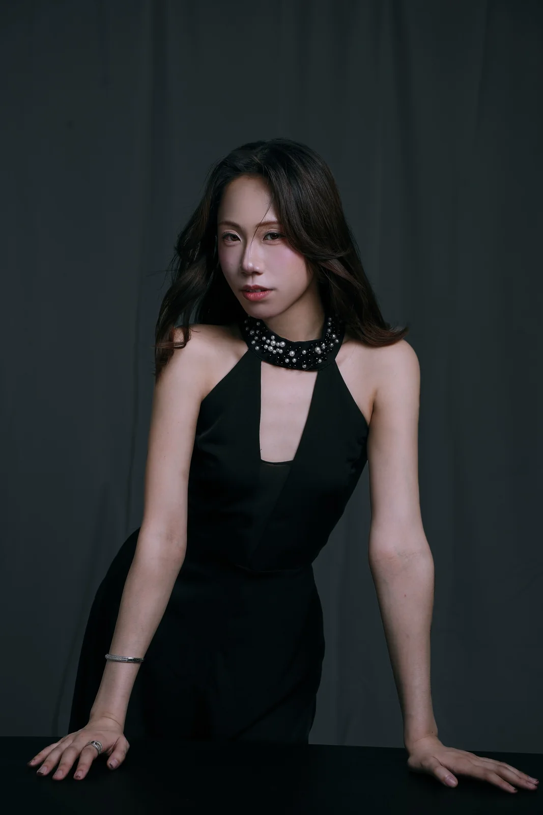 Nico in a black halter dress with a jewelled collar, leaning on a table in the studio