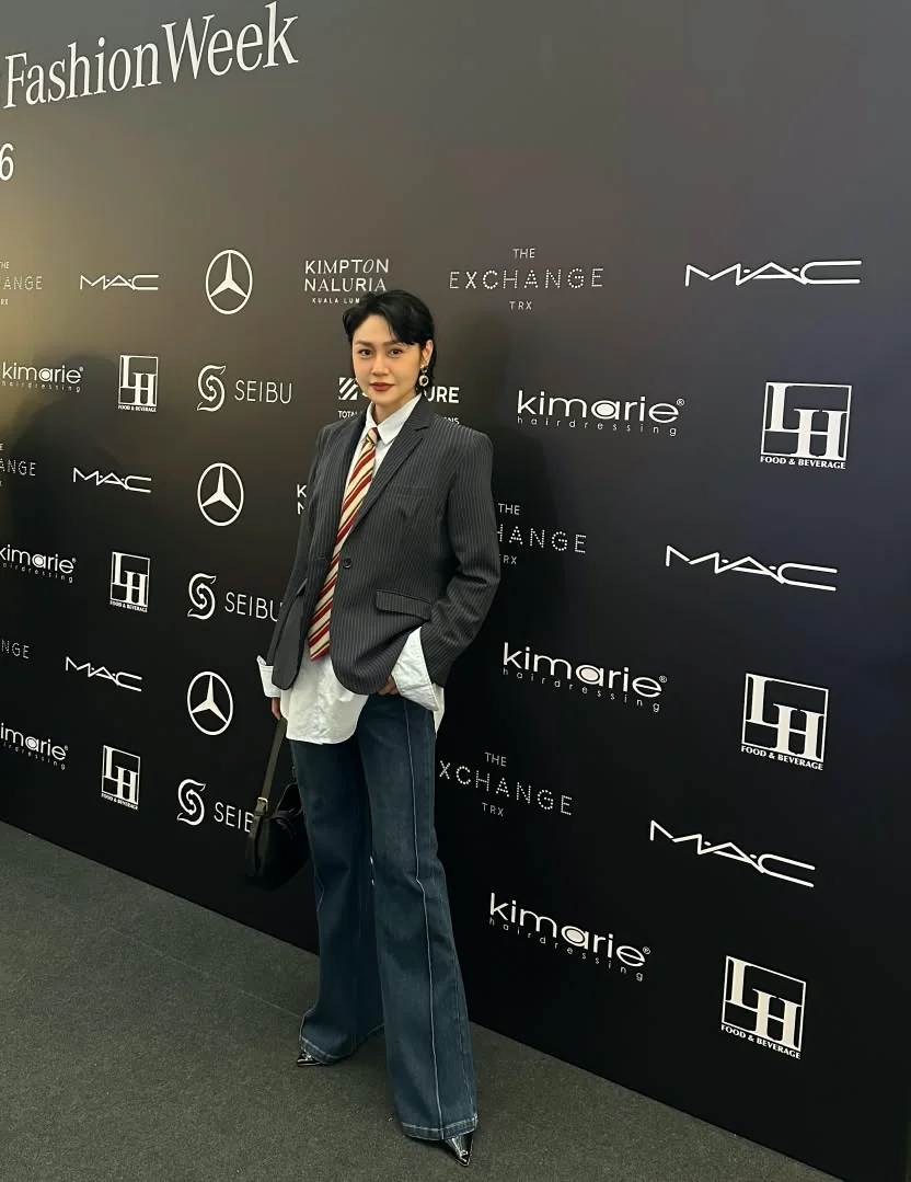 Standing in a pinstriped suit and tie at the Kuala Lumpur Fashion Week 2026 media wall