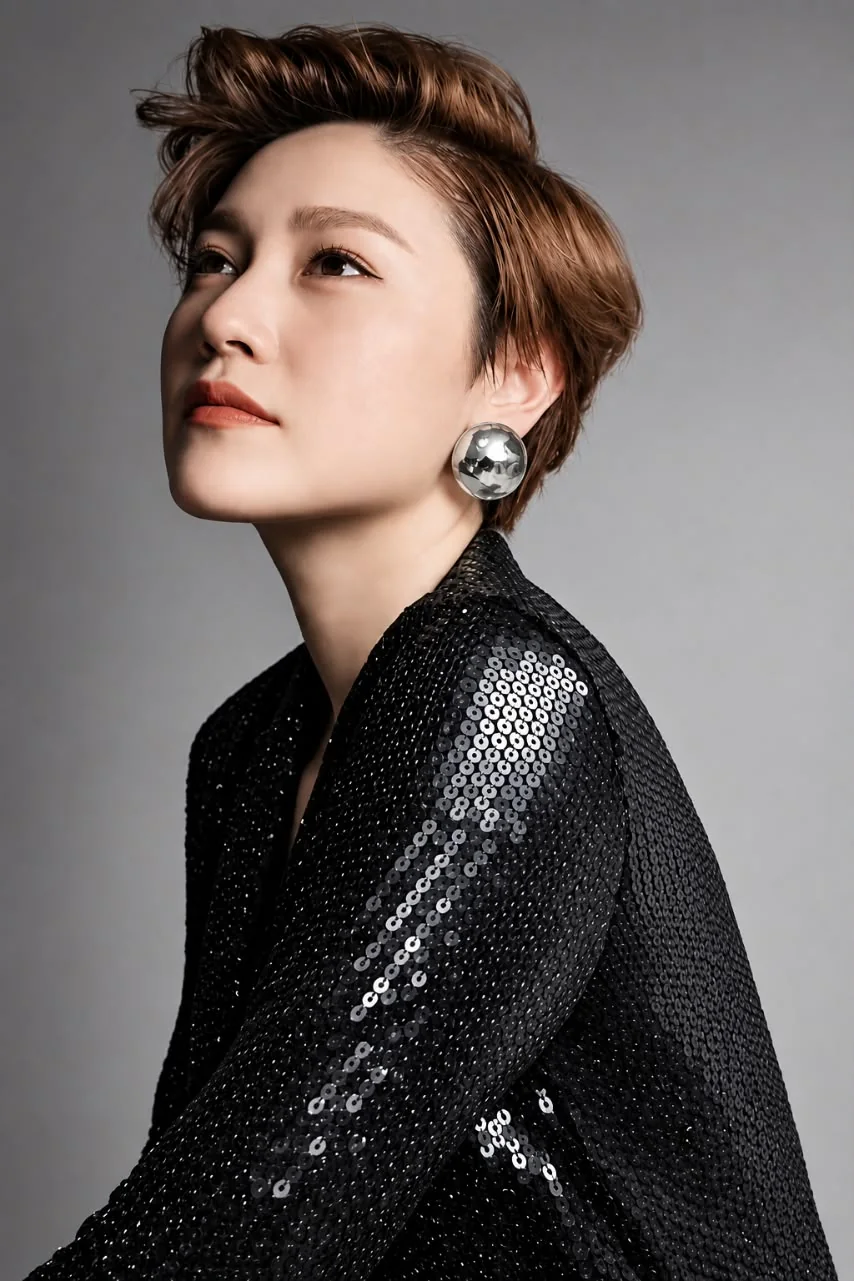 Studio portrait: a model with short swept-back hair in a sequinned jacket, looking up